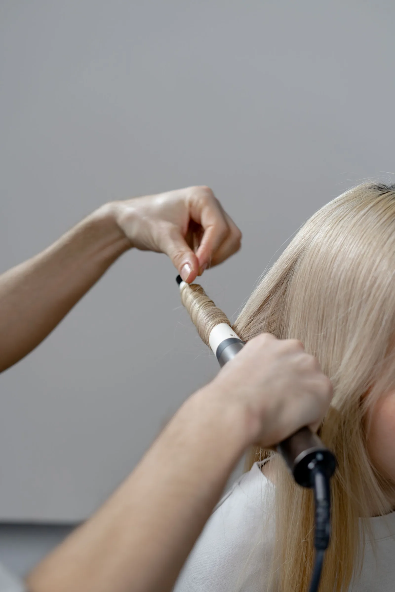 A stylist curling a client's hair