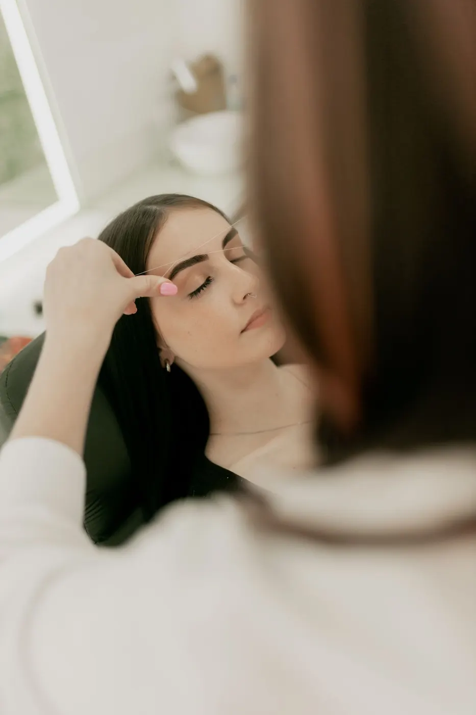 Esthetician performing a facial treatment on a relaxed client