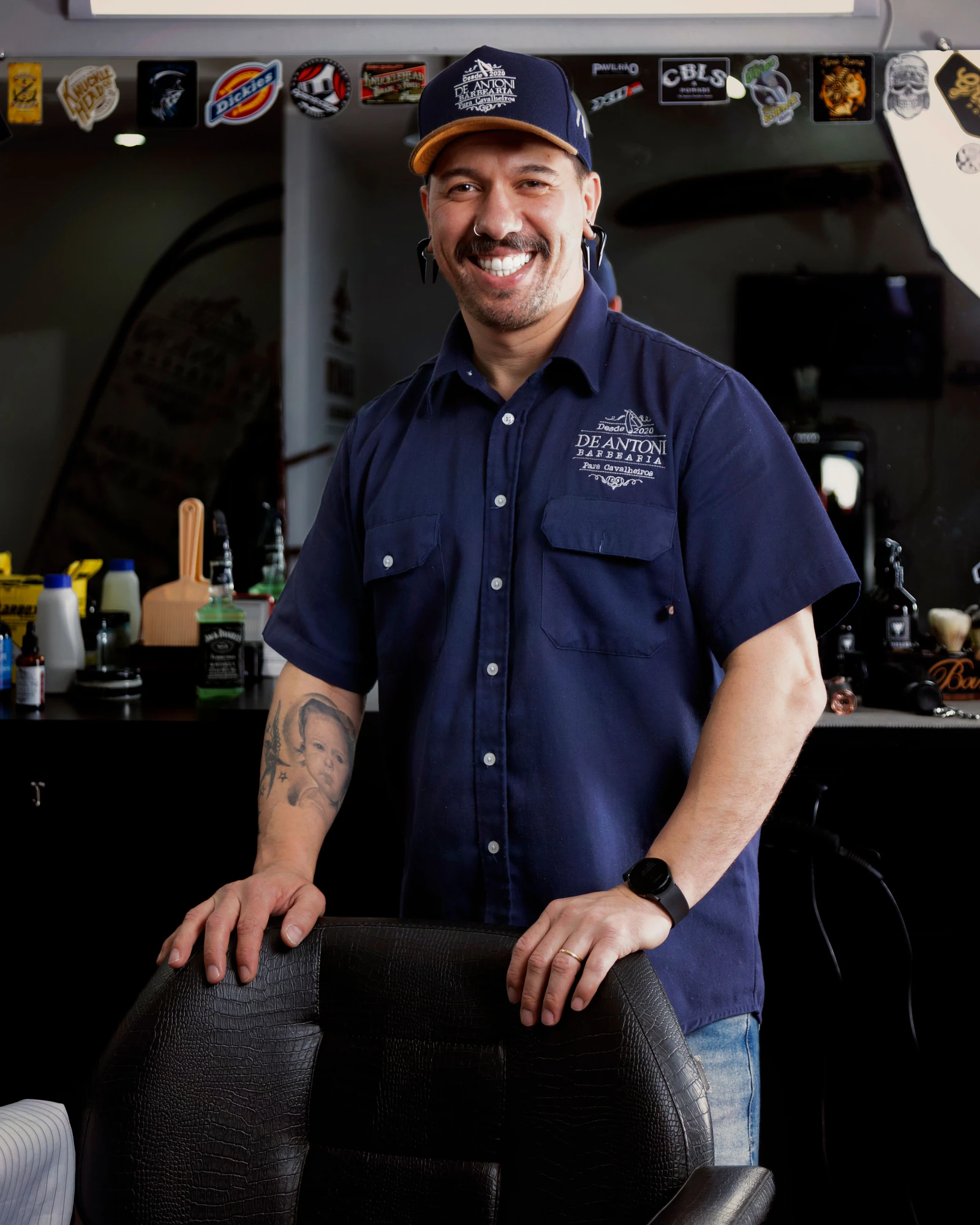 A barber smiling behind his chair in the shop