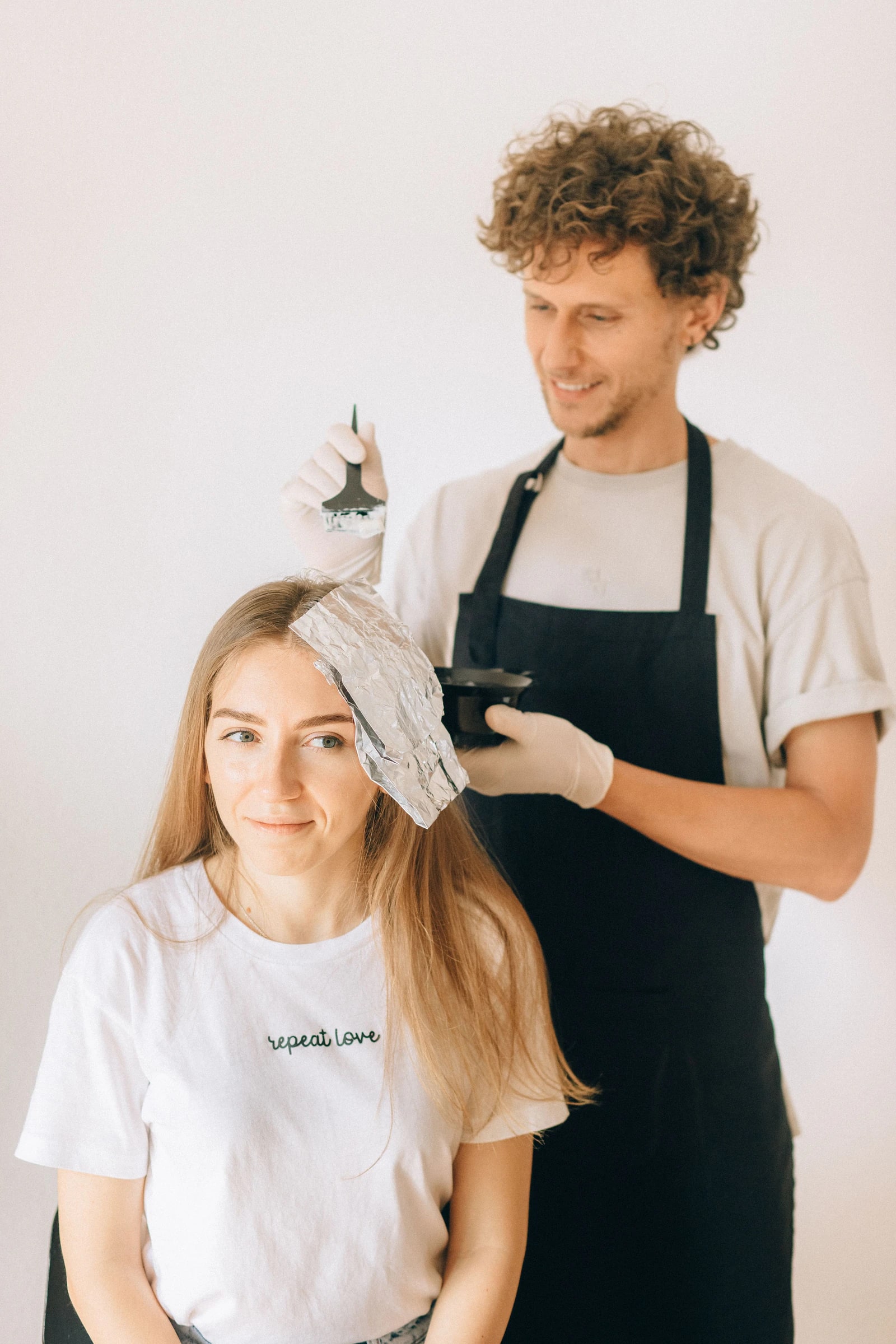 A colourist painting a foil on a smiling client's hair