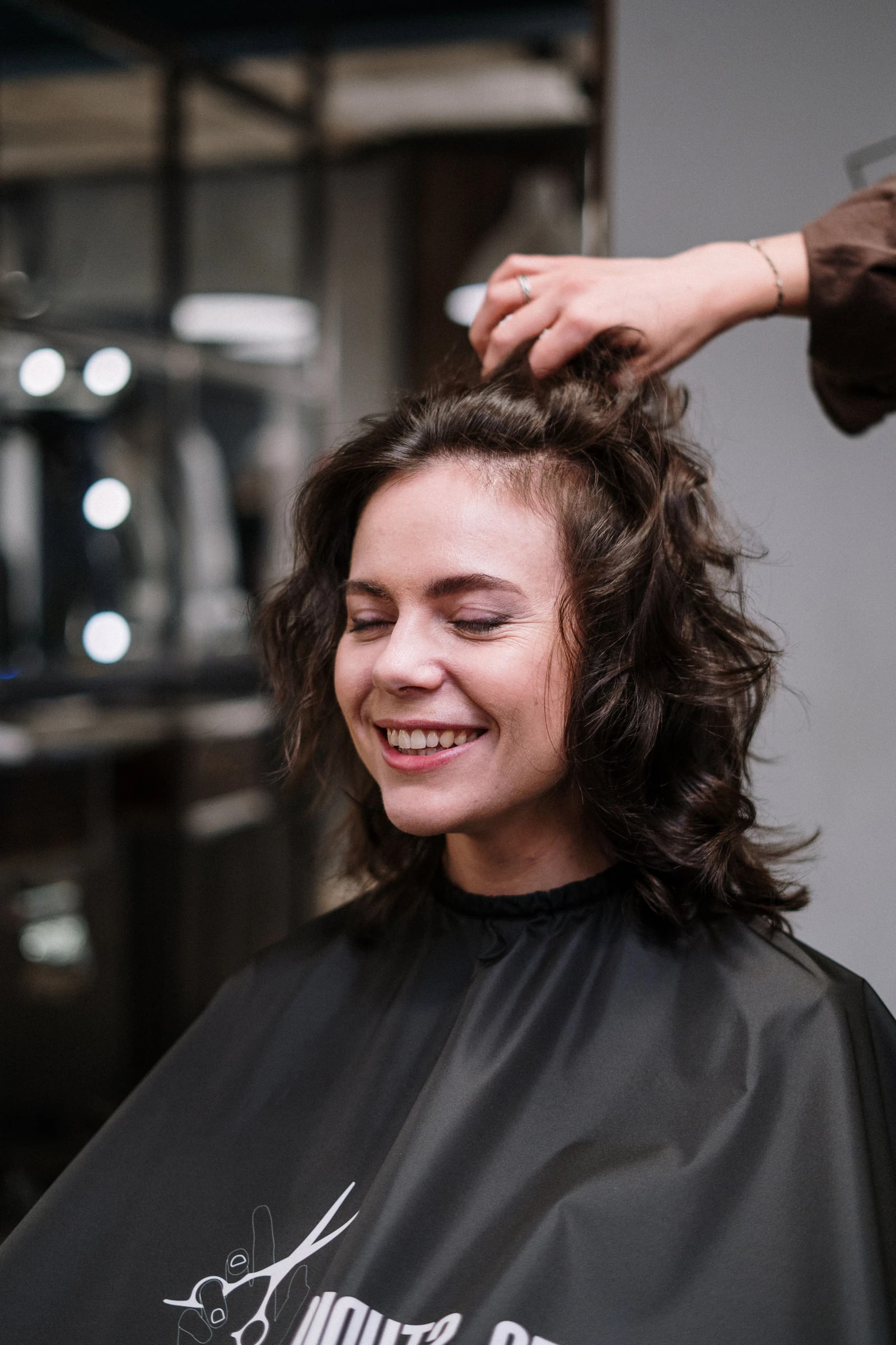 A client laughing in the salon chair with fresh curls