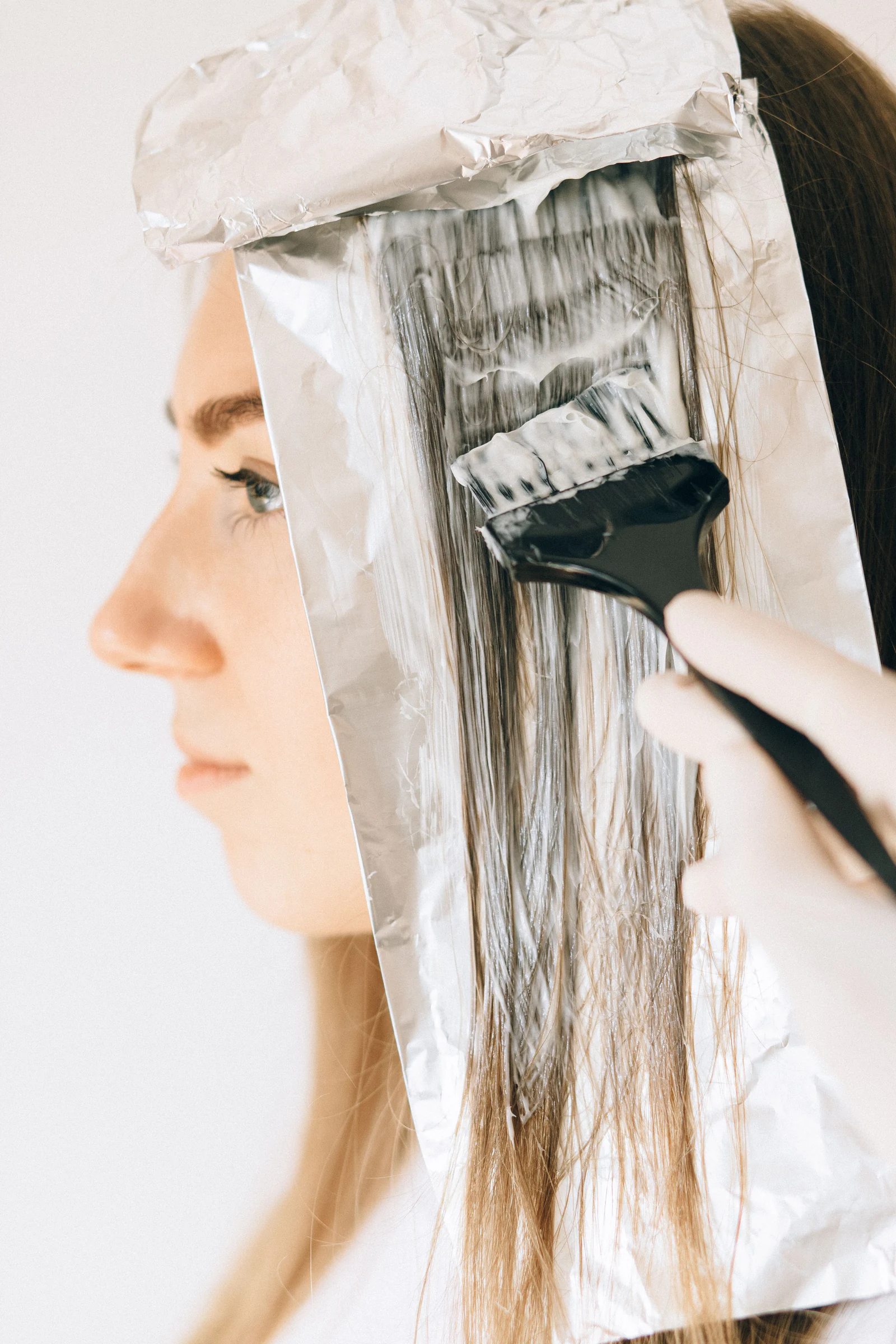 A client in profile with colour being brushed onto a foil