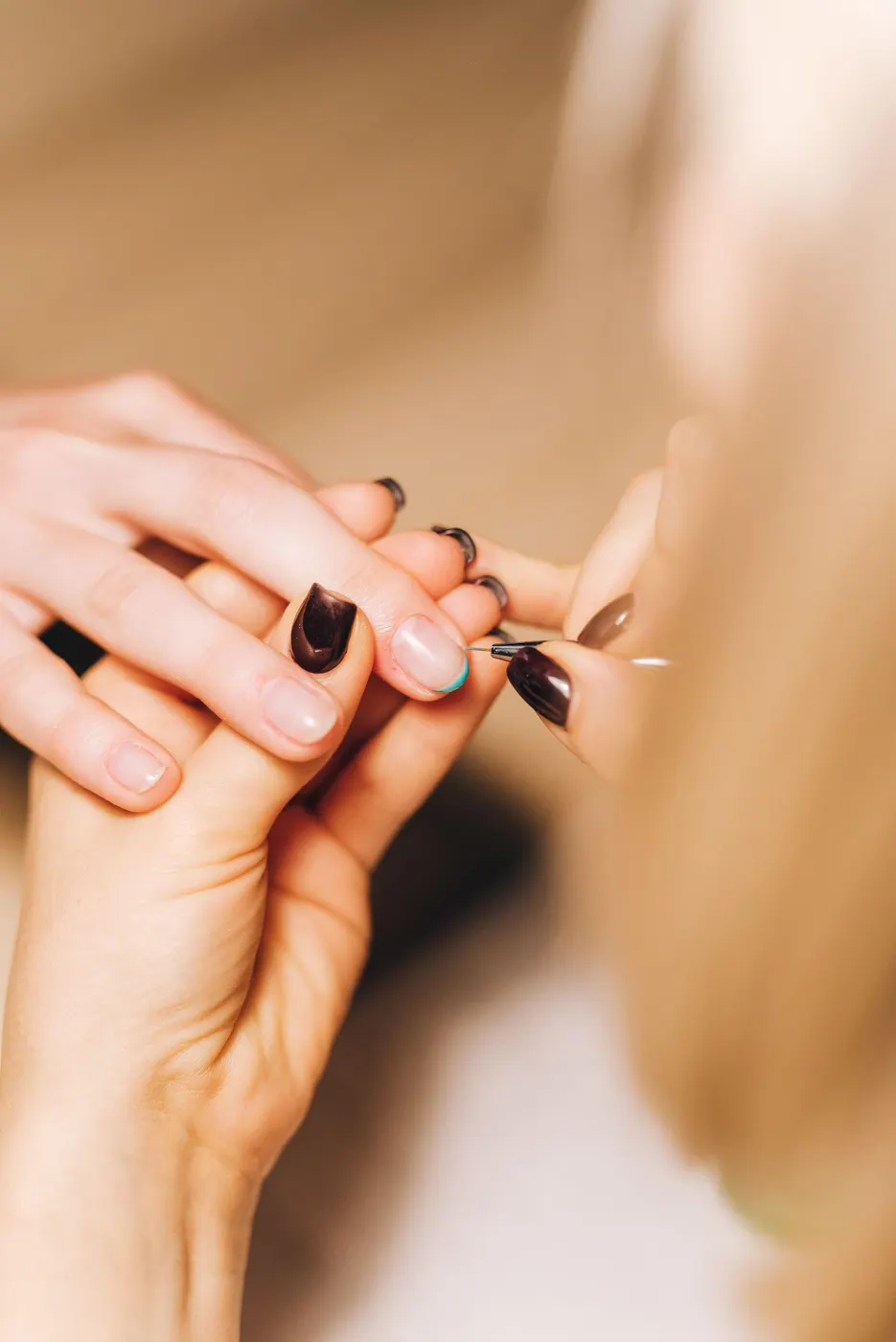 A nail artist painting the finishing detail on a client's nails