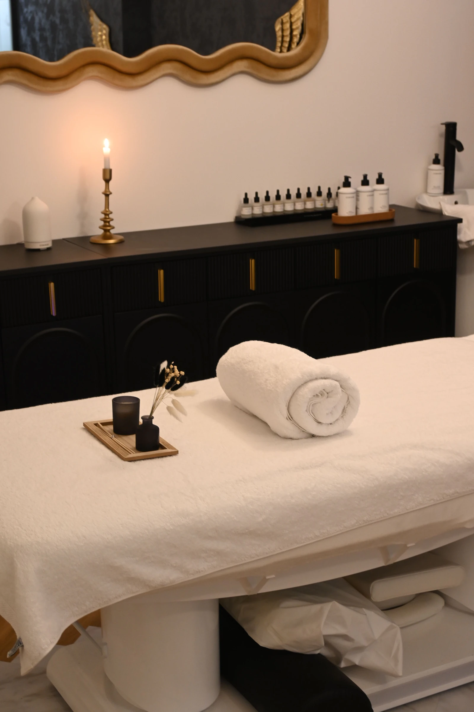 A treatment bed with a rolled towel and a candle