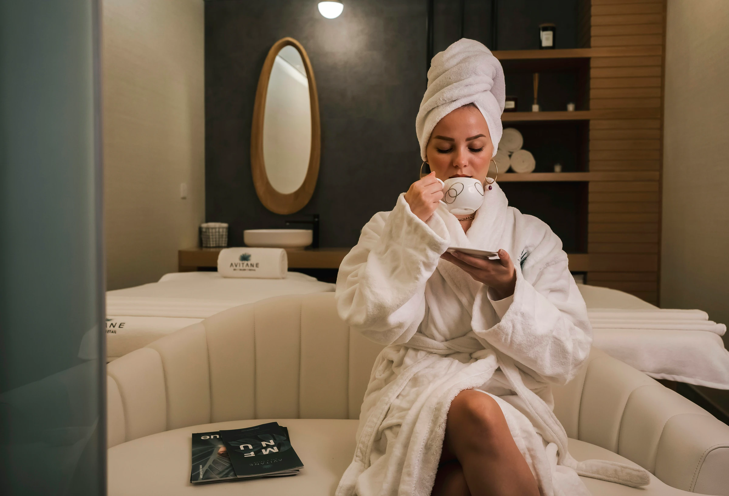 A client in a robe with a cup of tea in the spa lounge