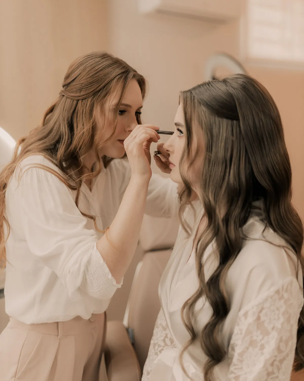A makeup artist applying eye makeup to a bride