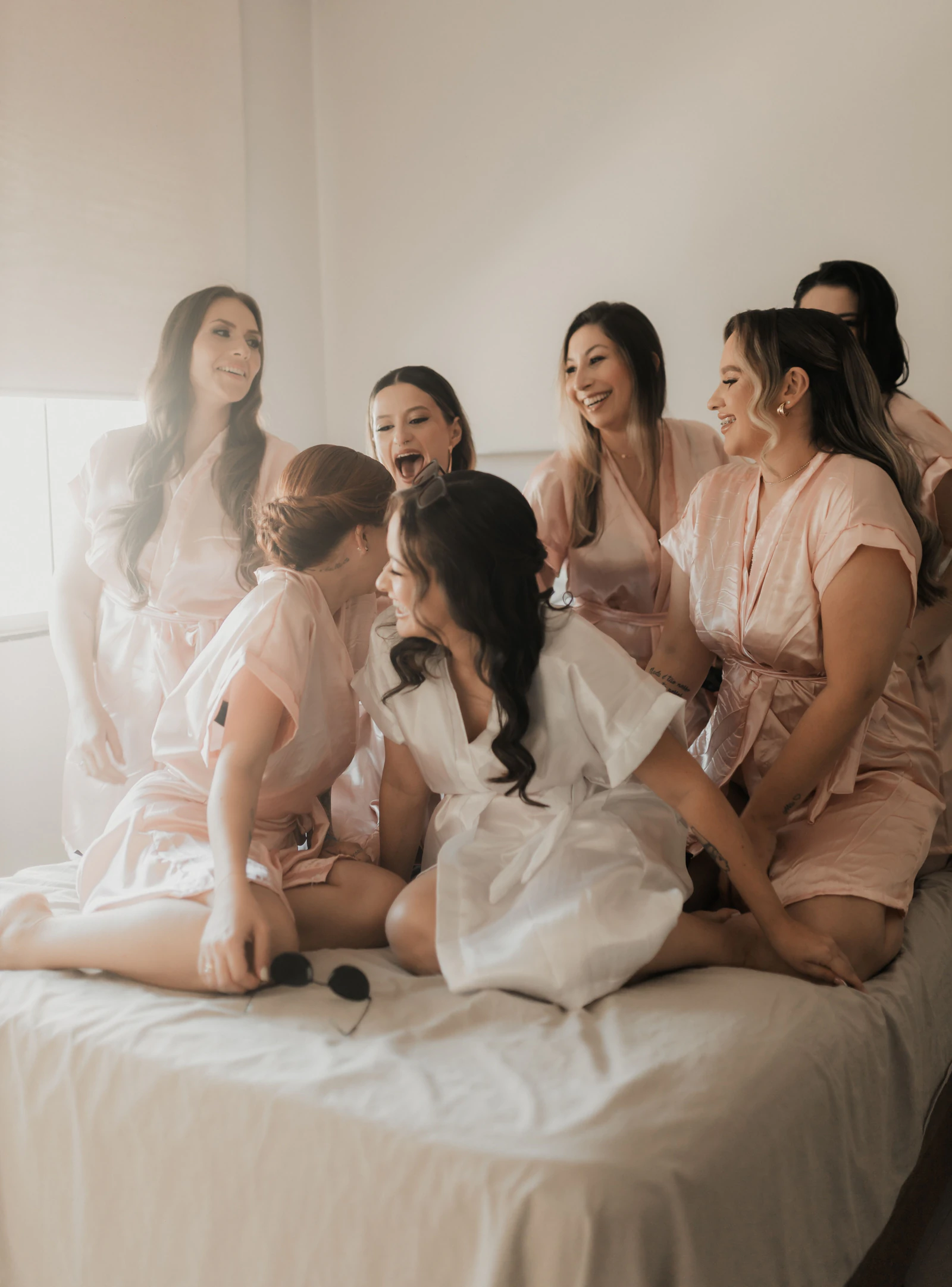 A bride and her bridesmaids laughing together in matching robes