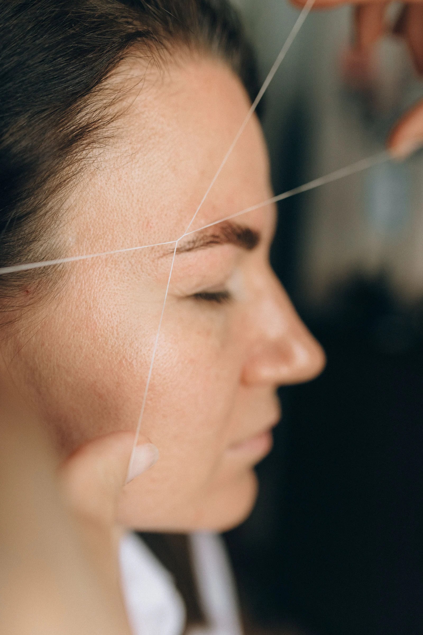 A brow artist threading a client's brows