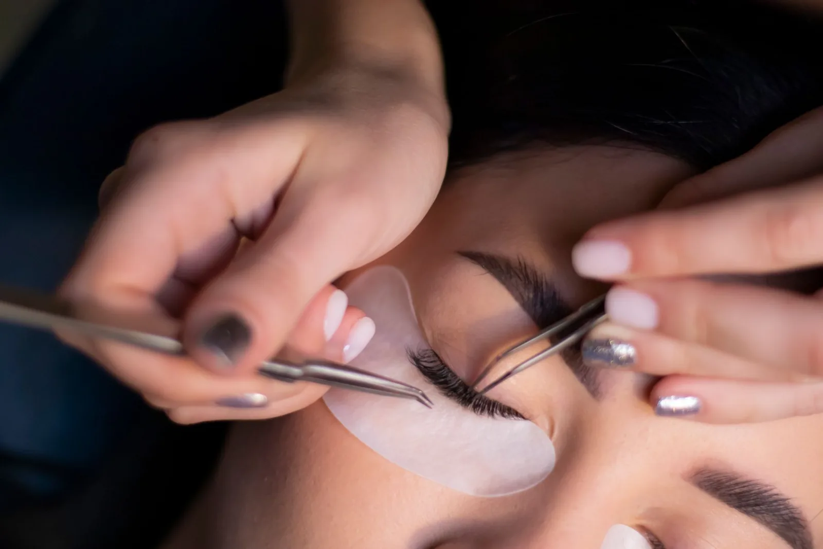 Lash artist applying eyelash extensions to a client