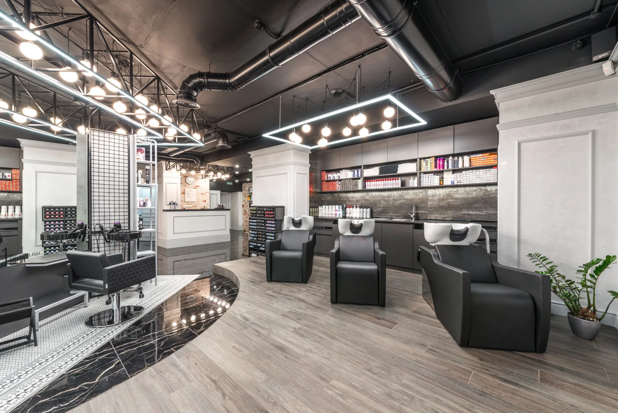 A modern salon with styling stations, wash basins and stocked product shelves