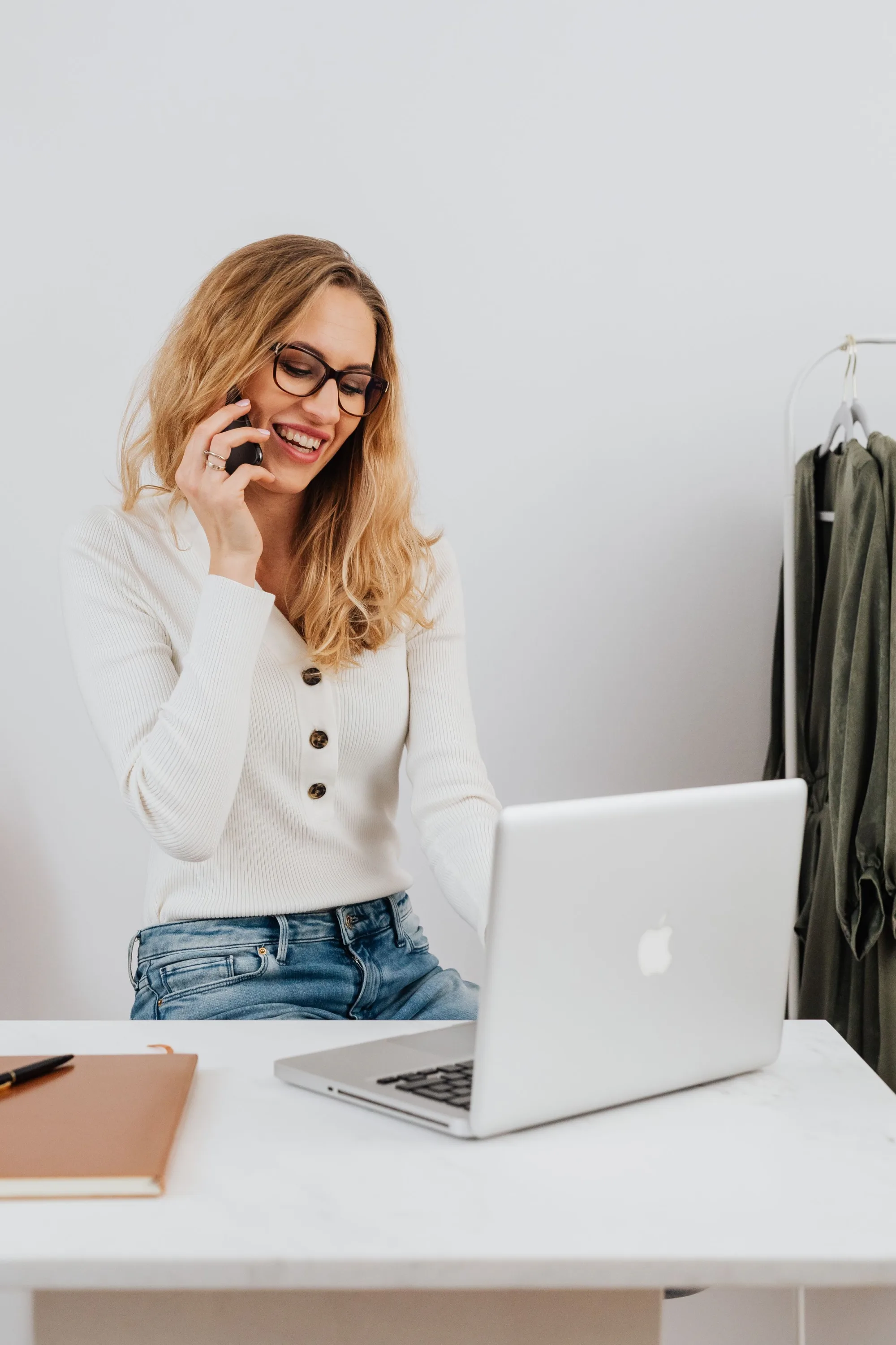 A studio owner laughing on a call at her desk