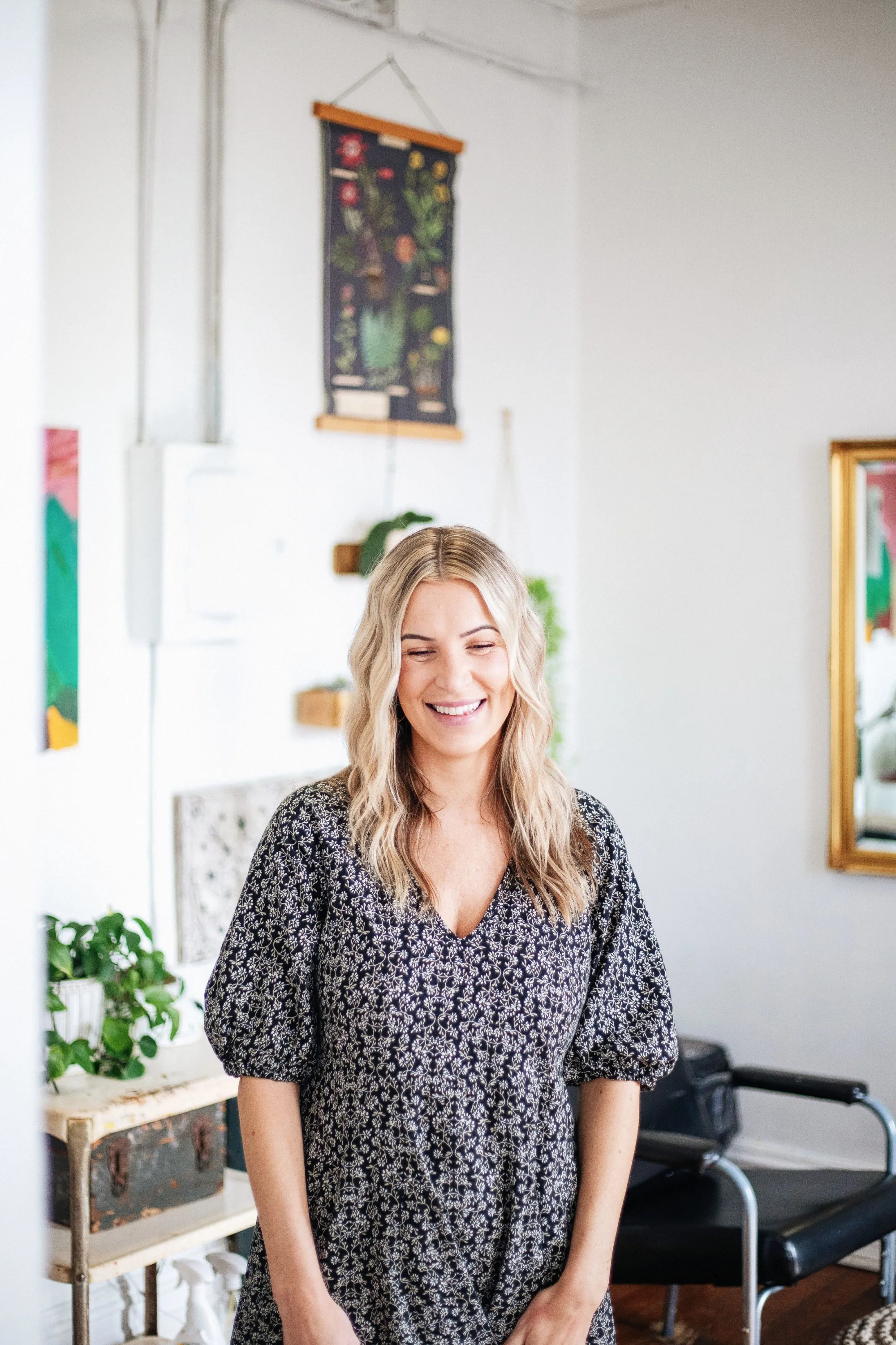 A salon owner standing in her salon between the chairs